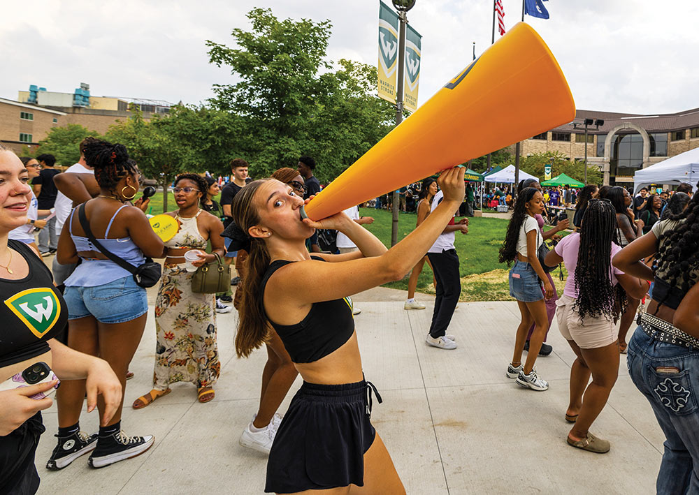 woman shouting into a large orange megaphone