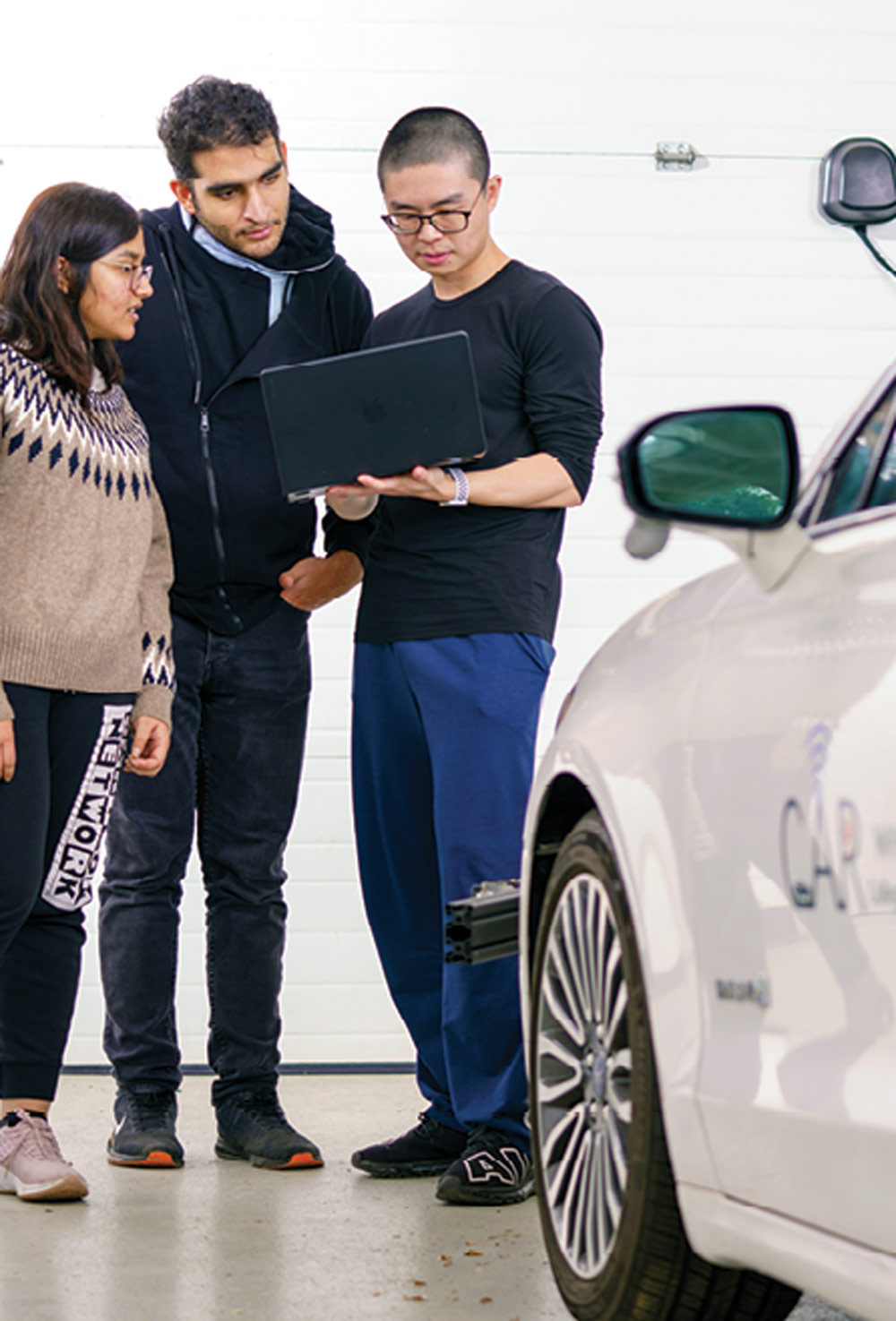 three engineering students overlooking laptop