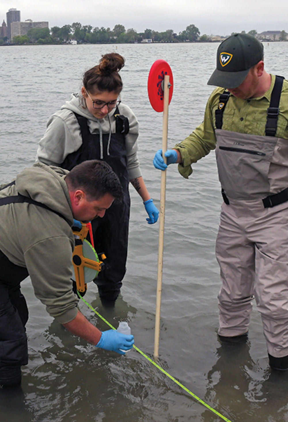 three researchers conducting environmental research in shallow water